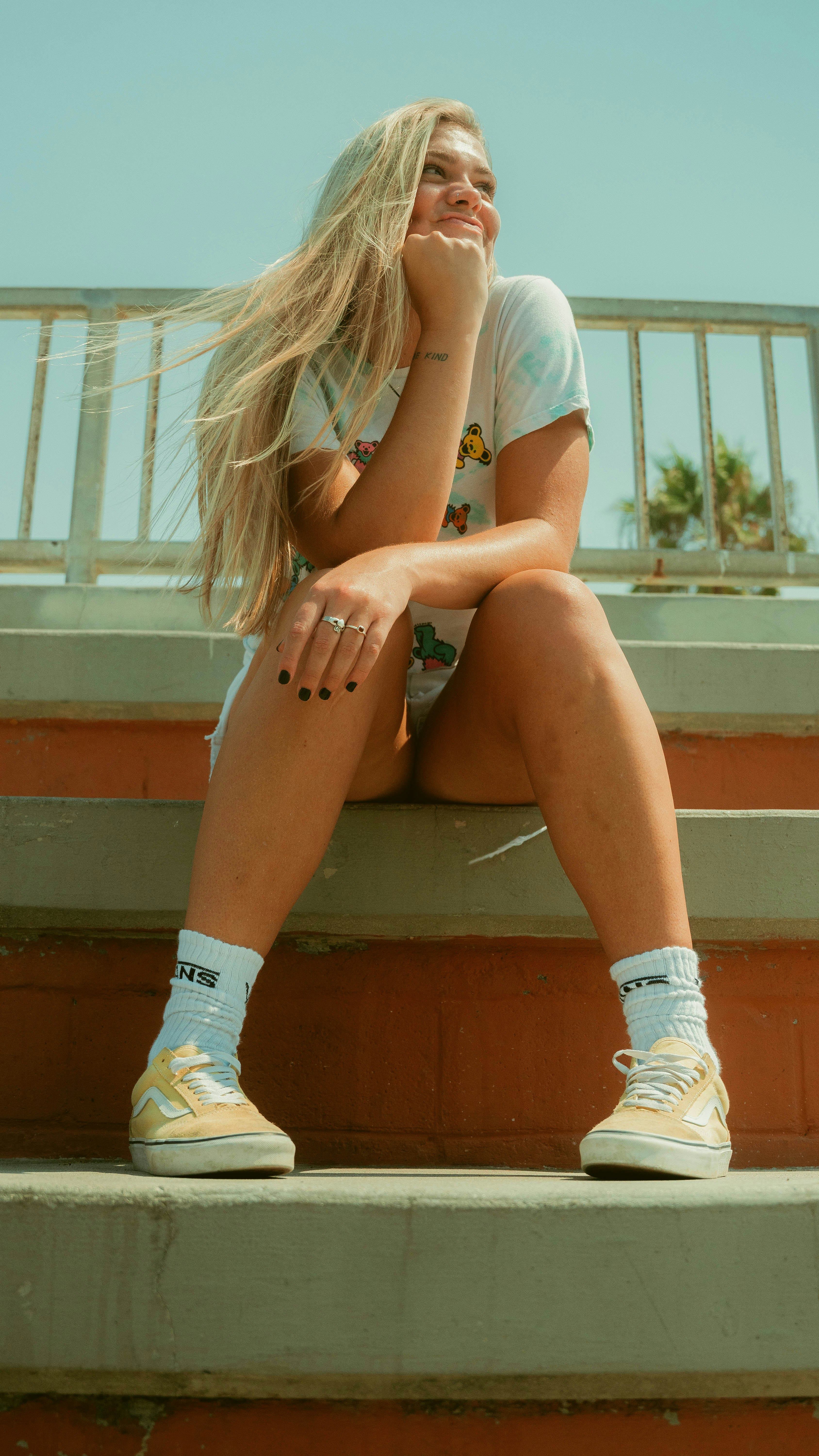 woman in white and blue bikini bottom and white sneakers sitting on brown concrete stairs